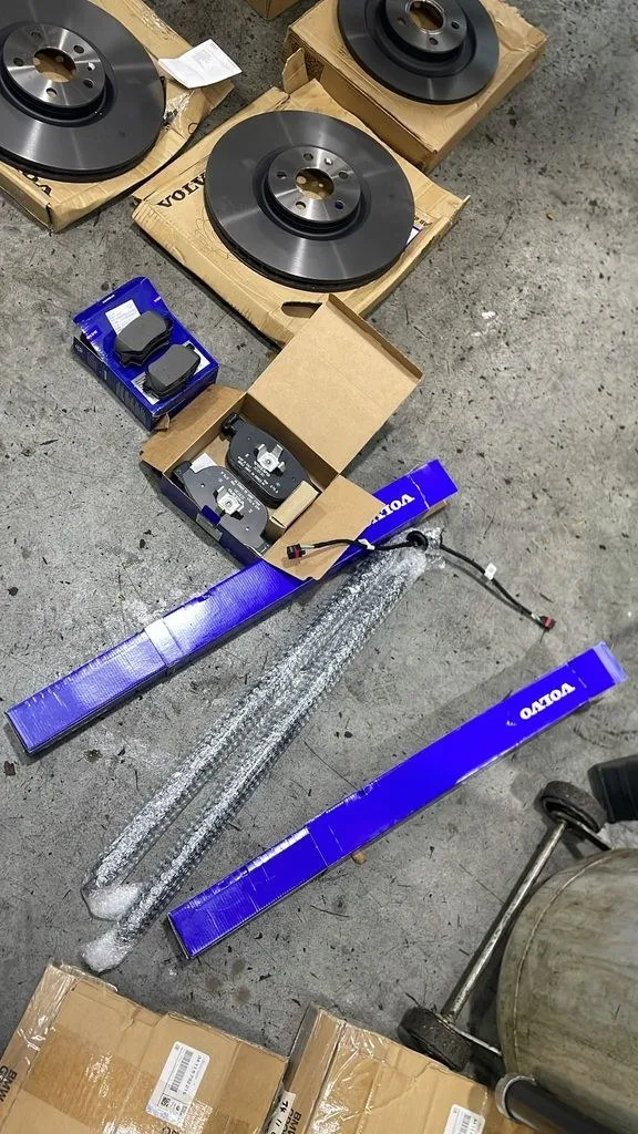 New Volvo front and rear brake discs, pads and a wear sensor laid out during a Volvo XC40 major service and brake replacement in Singapore