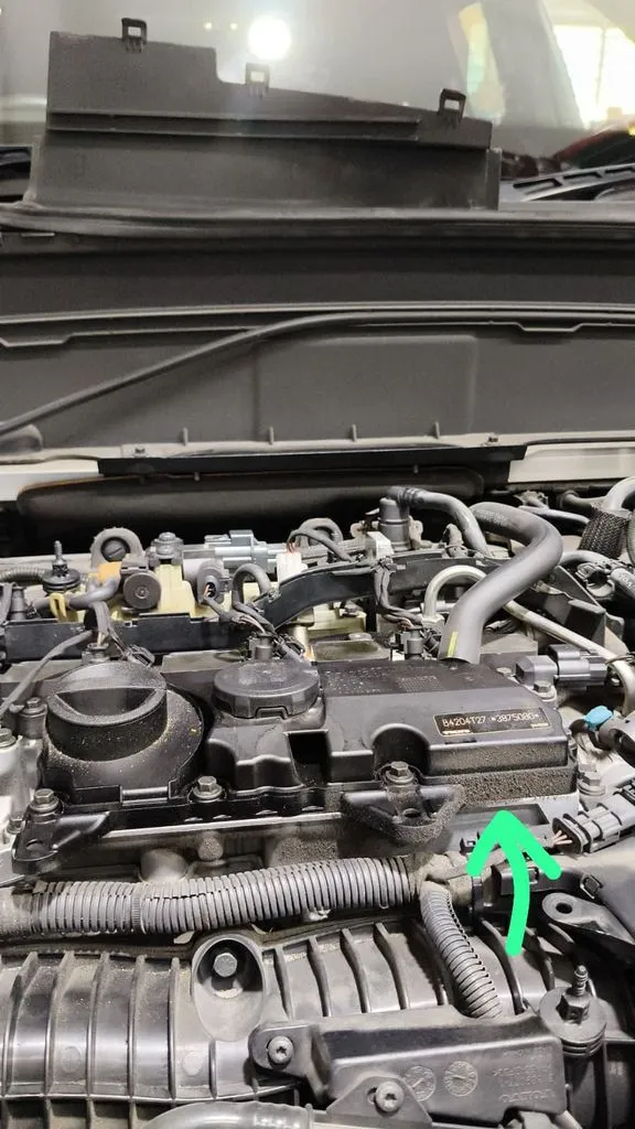 Volvo XC90 engine bay with a green arrow marking the location of the engine mount and oil leak during diagnosis