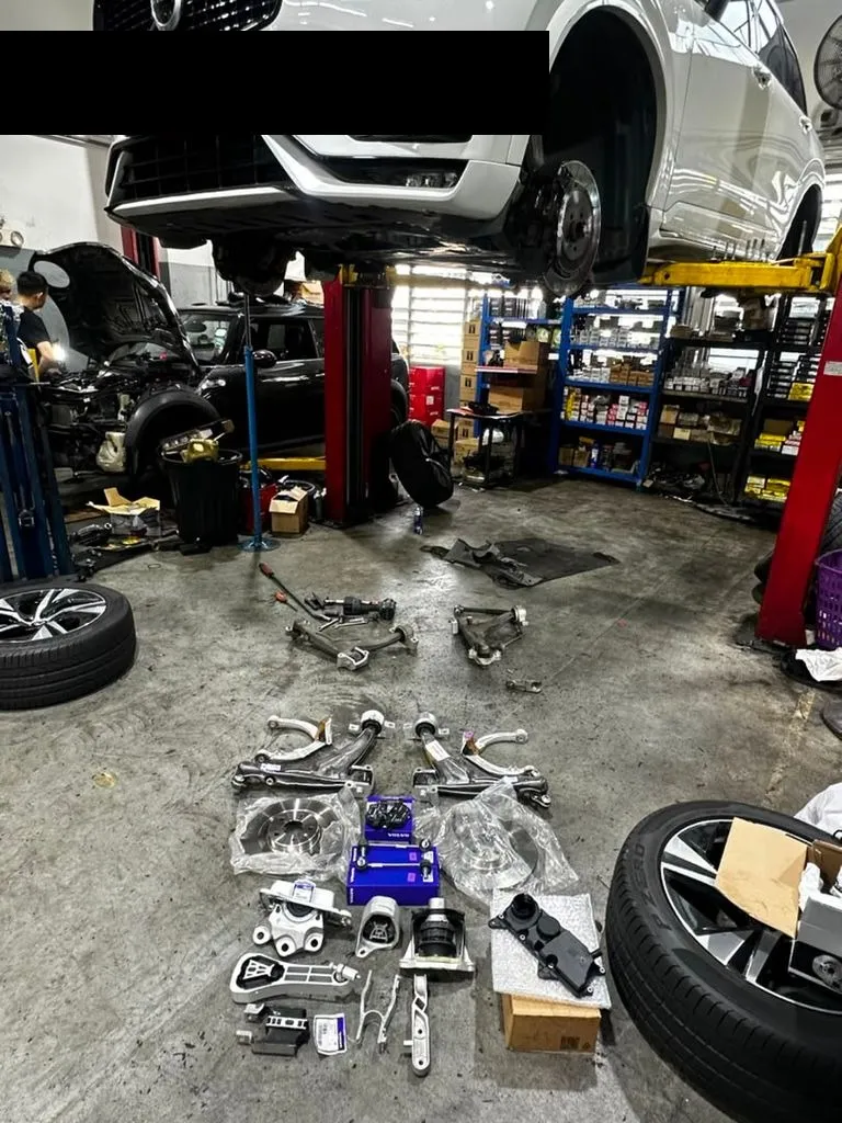Volvo XC90 on the lift with suspension arms and parts laid out on the workshop floor during inspection
