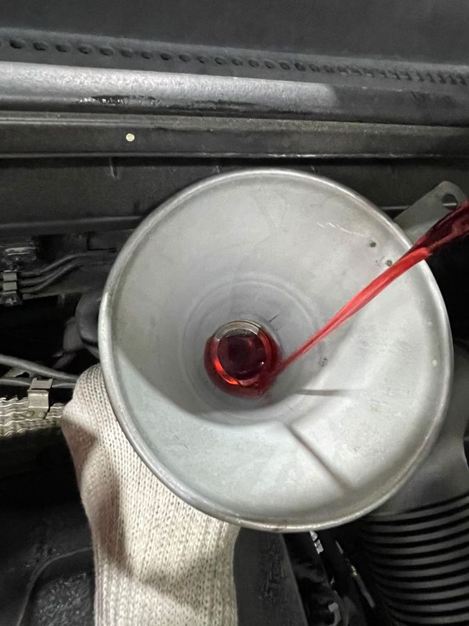 ATF transmission fluid being poured through a funnel during the Kia Sportage major service
