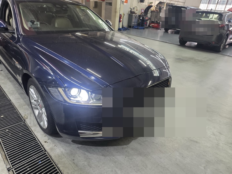 Jaguar XF sedan parked in a workshop garage, front view