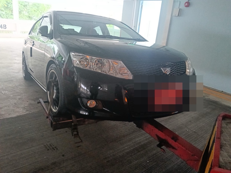 Toyota Corolla Axio being transported by flatbed tow truck for workshop service